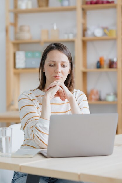 Een europese vrouw in haar thuiskantoor werkt met een laptop of kijkt naar een webinar