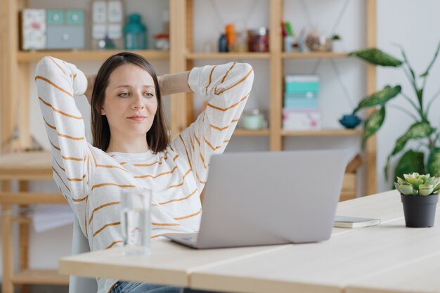 Een Europese vrouw in haar thuiskantoor werkt met een laptop of kijkt naar een webinar