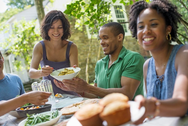 Een familie die in de zomer mannen, vrouwen en kinderen rond een tafel in een tuin verzamelt