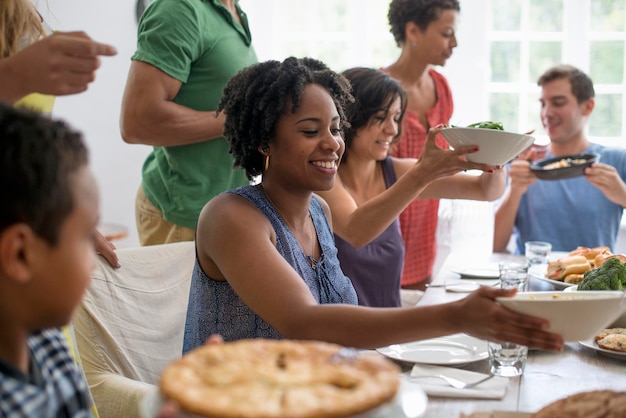 Een familie die mannen, vrouwen en kinderen verzamelt rond een eettafel en een maaltijd deelt