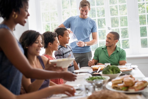 Een familie die mannen, vrouwen en kinderen verzamelt rond een eettafel en een maaltijd deelt