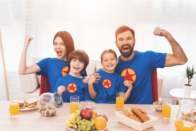 Een familie superhelden zit aan een tafel.