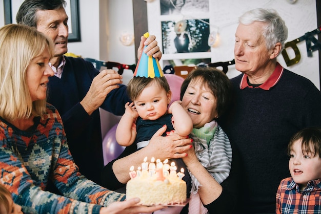 Een familie verzameld om een verjaardagsfeestje van een eenjarig meisje te vieren 39 Een taart met veel kaarsen