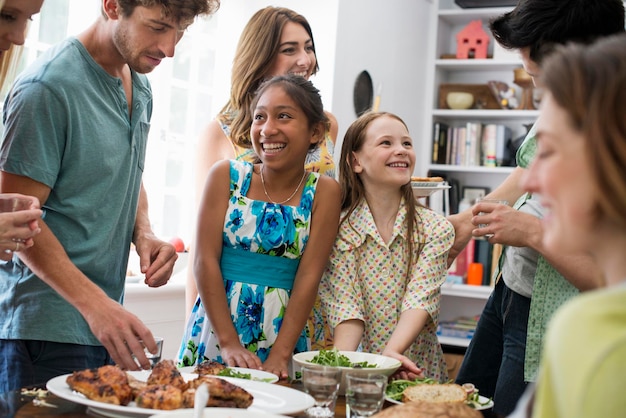 Een familiebijeenkomst voor een maaltijd Volwassenen en kinderen rond een tafel