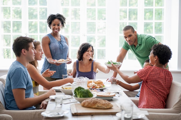 Een familiebijeenkomst voor een maaltijd volwassenen en kinderen rond een tafel