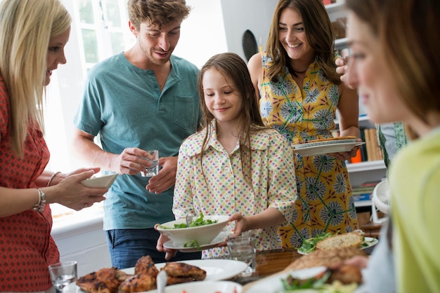 Een familiebijeenkomst voor een maaltijd Volwassenen en kinderen rond een tafel