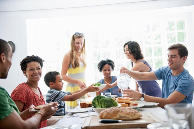 Een familiebijeenkomst voor een maaltijd Volwassenen en kinderen rond een tafel