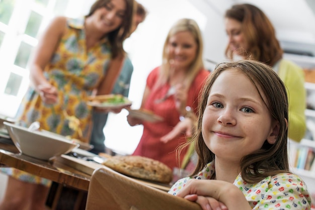 Een familiebijeenkomst voor een maaltijd Volwassenen en kinderen rond een tafel