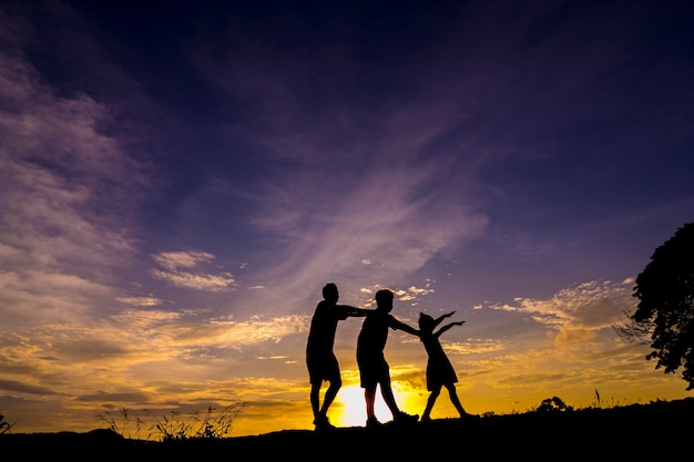 Een familiesilhouetten die bij zonsondergang spelen