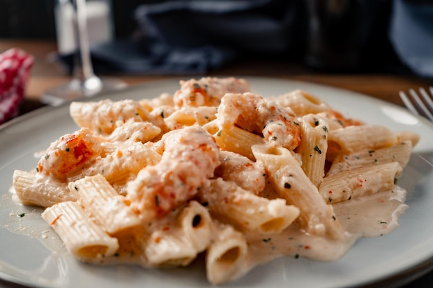 Een fijngesneden uitzicht van droge penne rigate pasta met een heerlijke garnaal en garnalenroom.