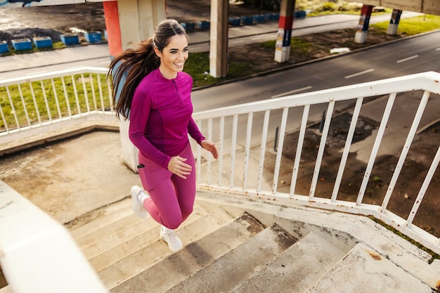 Een fit sportvrouw loopt de trappen op in de stad.