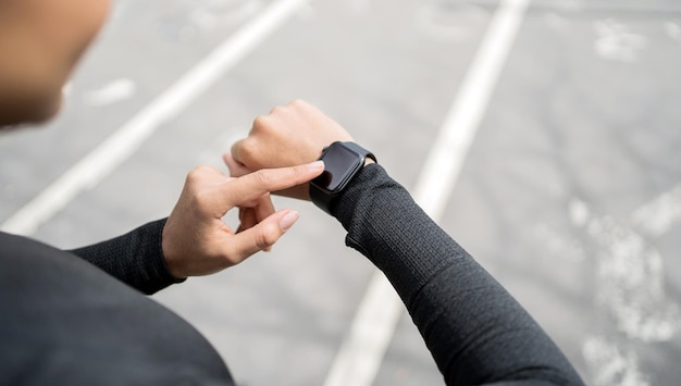Een fitnesshorloge en een hardloop-app zijn bij de hand Een vrouw in een strak trainingspak en traint buiten