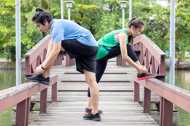 Een fitnesspaar strekt zich uit in het park. In de ochtend oefenen een jonge man en een jonge vrouw samen. Na het joggen doet een stel wat rekoefeningen.