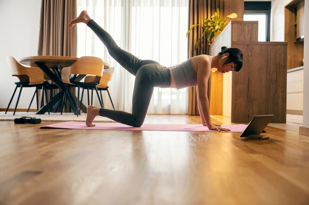 Foto een fitte japanse vrouw beoefent thuis fitness oefeningen op een online les.