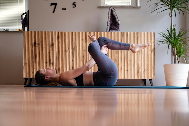 Een fitte jonge vrouw die zich strekt na een trainingsroutine thuis