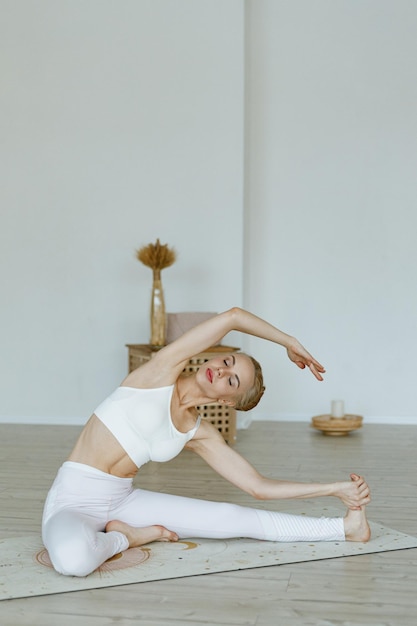 Een fitte vrouwelijke instructeur traint op een yogamat in een lichte studio