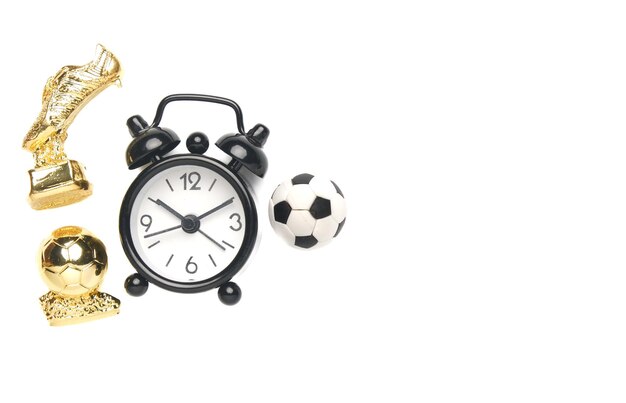 Foto een flatlay-afbeelding van de gouden bal van de wekkerbal en de gouden laars op een witte achtergrond van de copyspace. tijd voor voetbalwedstrijd