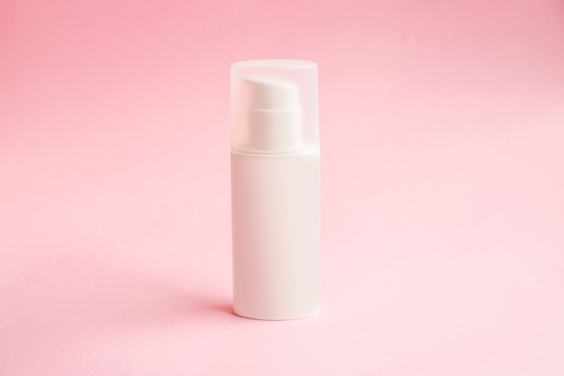 Een fles crème met dispenser op roze achtergrondmodel. beauty spa medische huidverzorging en cosmetische lotioncrème