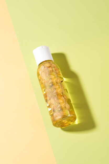 Een fles etherische olie van jasmijn met jasmijnbloemen erin liggend op een lichtgroene achtergrond Cosmetische etherische olie voor lichaamsbaden Fytotherapie aromatherapie anti-stress zelfzorg bovenaanzicht