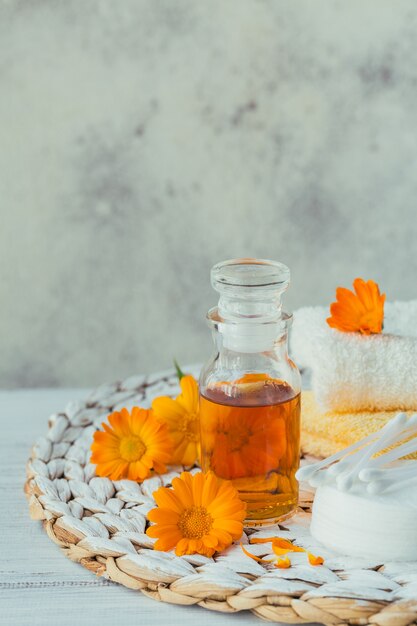 Een fles goudsbloemtint of aftreksel met verse calendulabloemen en wattenschijfje en stokken op een wit. Natuurlijke alternatieve geneeswijzen, geneeskrachtige kruiden en geneeskrachtige kruiden.