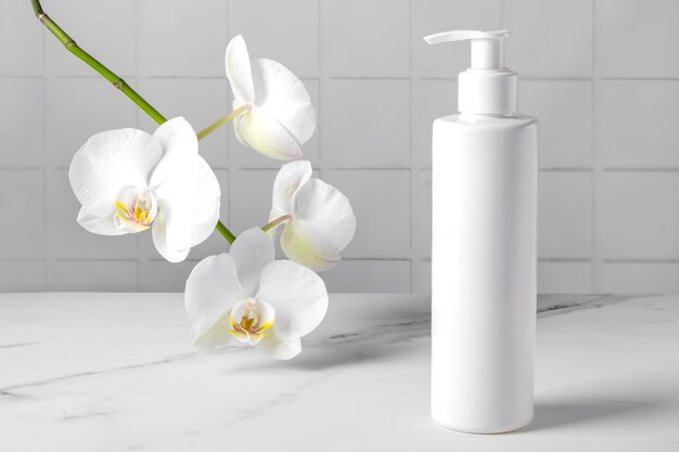 Een fles met een cosmetisch product tegen de achtergrond van een bloeiende orchidee