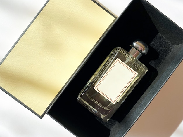 Een fles parfum uit een gele doos op een witte geïsoleerde achtergrond