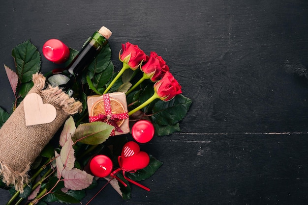 Een fles rode wijn en een boeket rode rozen. Valentijnsdag. Op een houten achtergrond. Bovenaanzicht. Vrije ruimte voor uw tekst.