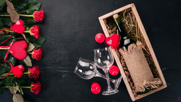 Een fles rode wijn en een boeket rode rozen. Valentijnsdag. Op een houten achtergrond. Bovenaanzicht. Vrije ruimte voor uw tekst.