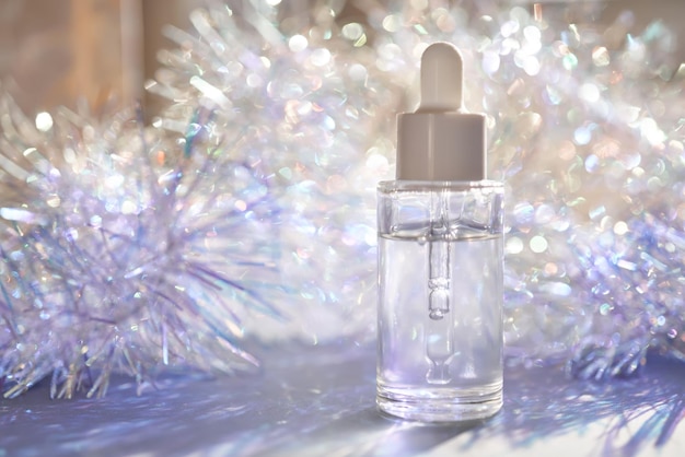 Een fles serum met een pipet in tinsel in een kerstthema in paarse tinten