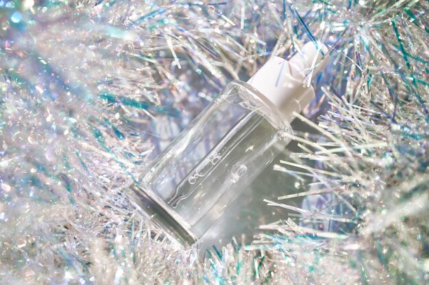 Een fles serum met een pipet in tinsel in een kerstthema in paarse tinten