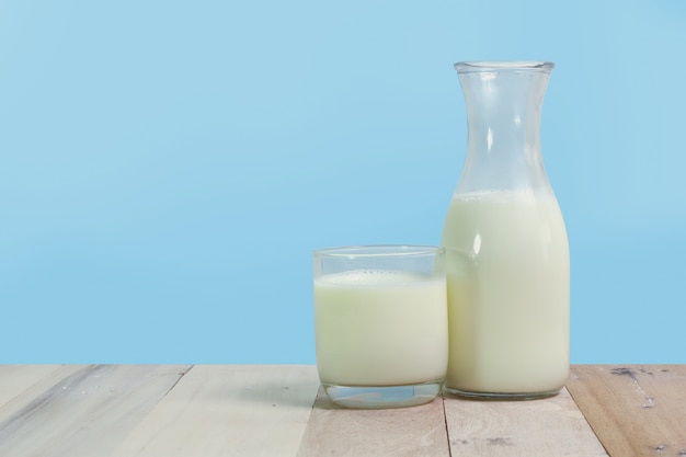 Een fles van rustieke melk en een glas melk op een houten tafel