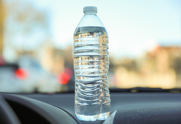 Een fles water staat op een dashboard van een auto.