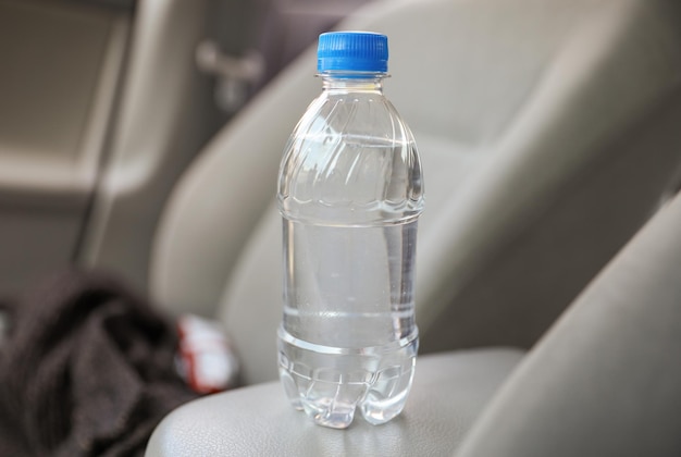 Een fles water staat op een stoel van een auto.