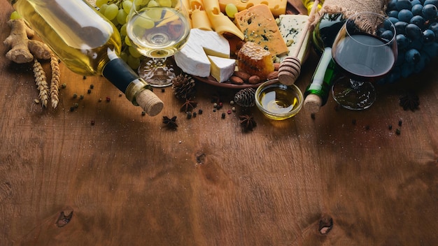 Een fles wijn en een groot assortiment kazen, honing, noten en kruiden op een houten tafel Bovenaanzicht Vrije ruimte voor tekst