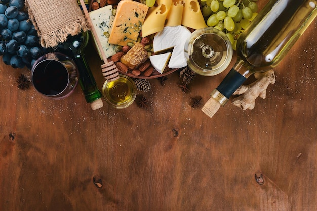 Een fles wijn en een groot assortiment kazen, honing, noten en kruiden op een houten tafel Bovenaanzicht Vrije ruimte voor tekst