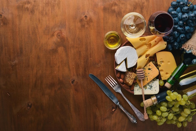 Een fles wijn en een groot assortiment kazen, honing, noten en kruiden op een houten tafel Bovenaanzicht Vrije ruimte voor tekst