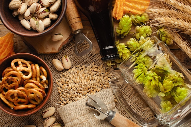 Een flesje bier met groene hop haver tarwe spikelets opener en glazen met donker en licht bier op zwart bekrast krijtbord Bovenaanzicht