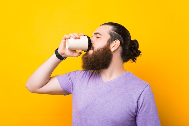 Een foto van een man met een baard die van zijn koffie geniet