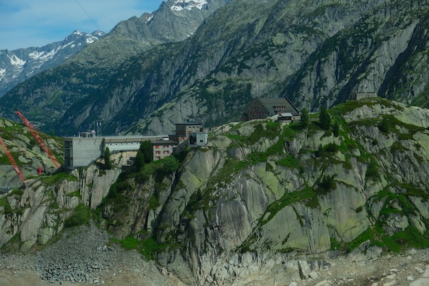 Een foto van een rotsachtige groene berg met bouwinzicht op de Grimselpas