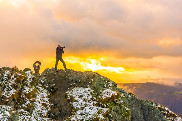 Een fotograaf bovenop de berg in de besneeuwde winteroranje zonsondergang, op de berg Peñas de Aya in de stad Oiartzun bij San Sebastian, Spanje