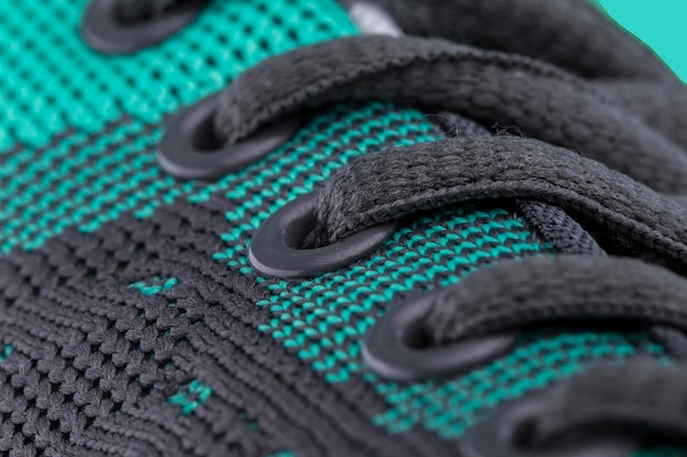 Een fragment van een groene sneaker met zwarte veters close-up Sneaker textuur