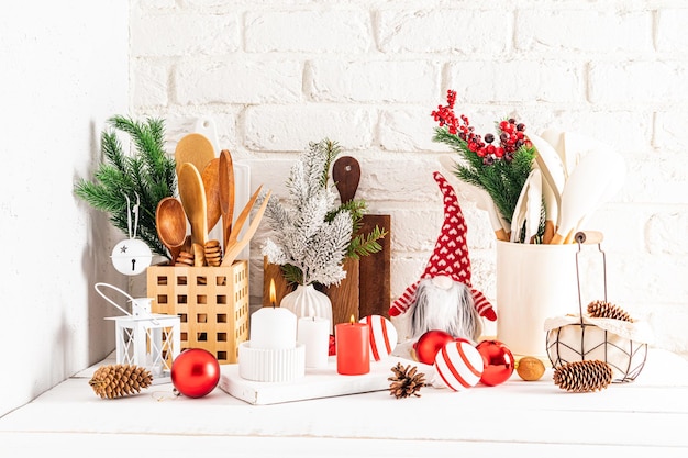 Een fragment van een wit houten aanrecht in de keuken met verschillende keukenartikelen en kerstversieringen in een moderne stijl gemaakt met hun eigen handen