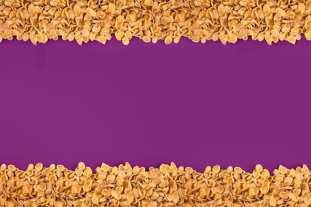 Een frame bekleed met cornflakes cornflakes verspreid over een paarse achtergrond ruimte kopiëren