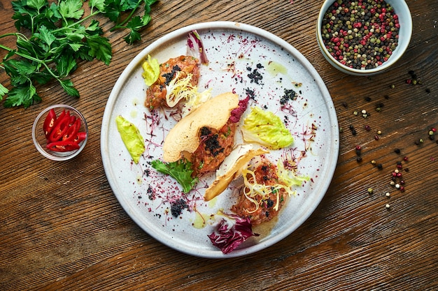 Een Frans voorgerecht voor het hoofdgerecht - zalm steak tartaar met zwarte kaviaar, roomkaas en croutons, geserveerd in een wit bord. Restaurant eten. Uitzicht van boven