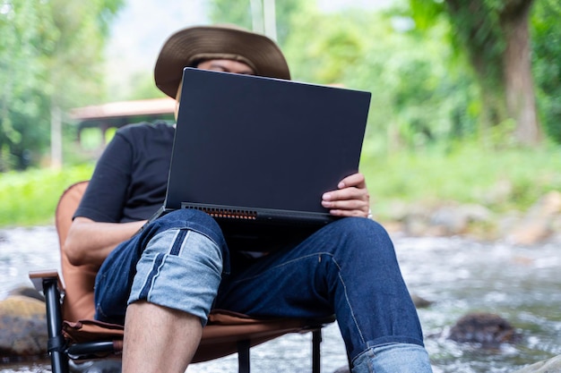 Foto een freelance man werkt op afstand in de natuur in het herfstbos landleven een pauze van de beschaving van life vibes een man met een laptop afstandsonderwijs in de frisse lucht via een laptop op afstand werken