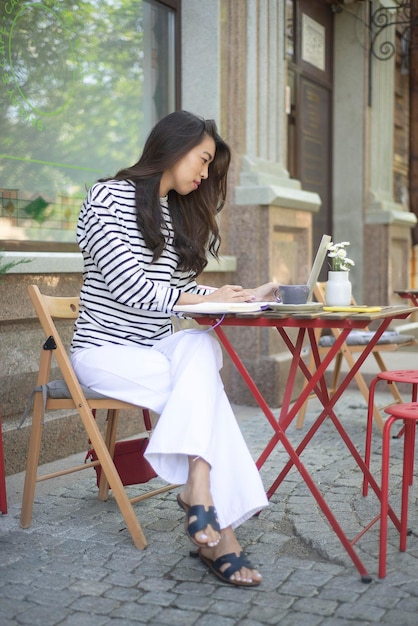 Een freelance meisje werkt op een computer op een terras