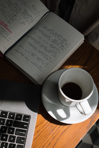 Een freelancer meisje werkt in een café op een laptop drinkt zwarte koffie en maakt aantekeningen in een notitieboekje