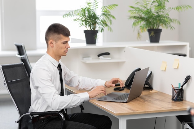 Een freelancer met een shirt gebruikt een laptop terwijl hij op kantoor zit en het nieuws leest