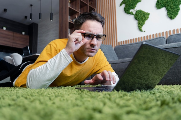 Een freelancer werkt vanuit huis doordachte man man liggend op de vloer met laptop