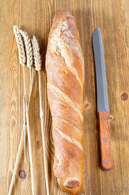 Een fris lichtgekleurd brood met een heerlijk knapperig, close-up in de keuken met een mes en aartjes van stronk